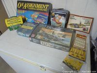 Wide view of entire lot showing various boxed model kits, board games, train supplies with original packaging, and a metal lunchbox.