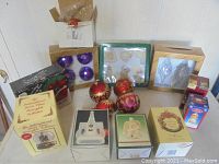 Full assortment of Christmas items including boxed ornaments, figurines, and loose glass baubles arranged on a surface against a white wall.
