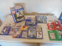 Overview of multiple Starting Lineup sports figurines and trading cards on white table showing a variety of players and sports.