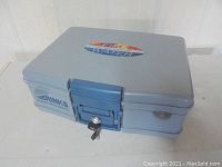 Light blue Brinks Home Security briefcase-style safe showing front and top details.