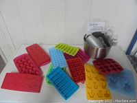 Overview of assorted colorful silicone candy molds and stainless steel mixing bowl with Sunbeam hand mixer inside.