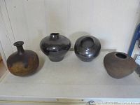 Four ceramic vases displayed side by side showing different shapes and finishes.