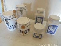 Photo showing all six kitchen canisters on a white surface, three with Yorkie dog and checkered design and three with "Scented Sachets" label
