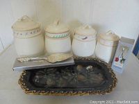 Four ceramic kitchen canisters with lids, rectangular decorative tray, silver metal cake server