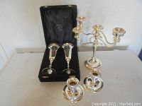 Full view of all items: pair of goblets in a black velvet case, triple-branch candelabrum and two smaller candlesticks grouped on a table.