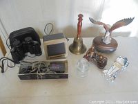 Wide view of lot including binoculars, Motorola speakers, wooden bell, glass insulator, decorative train, glass car, wooden eagle figurine.