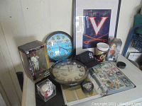 Overview of lot showing bobblehead, clocks, baseball cap, cards, framed print, puck, and cup.