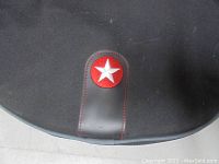 Close-up of red circular badge with white star on black fabric of the gig bag.