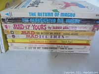 Stack of nine vintage paperback books with titles visible showing Mr. McGoo and MAD series.
