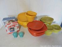 Photo showing assorted yellow, orange, and olive green Tupperware bowls with lids, and turquoise salt and pepper shakers, including one in box.
