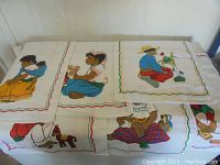Embroidered towels featuring children in traditional western clothing, colorful fabric with detailed stitching.