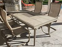 Outdoor dining set photo showing 4 chairs and rectangular table with stone tile top, tiles show cracks and stains.