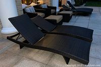 Front view of two dark brown polyrattan woven sunloungers with adjustable backrests; two more visible in background