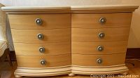 Front view of eight-drawer wooden dresser showing curved front and metal round drawer pulls