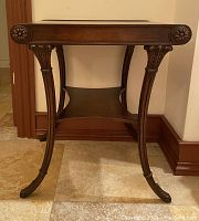 Front view of dark wood accent table showing elegant curved legs with floral carving and bottom shelf