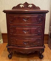 Front view showing detailed carvings on three curved drawers and the carved top back panel.