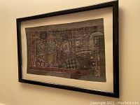 Framed embroidered tapestry with detailed geometric patterns and black frame