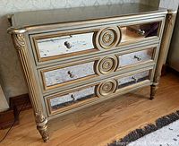 Front view of dresser showing mirrored drawer fronts with gold accents and round knobs.