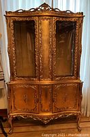 Front view of the Italian gold china cabinet showing ornate carvings, glass doors, and lower storage compartments.