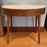 Front view of oval writing desk showing marble top, drawer, legs and scratch on front right leg