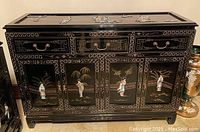 Front view of large credenza showing three top drawers with geometric gilt borders and four lower doors with hand painted Oriental figures and carved accents