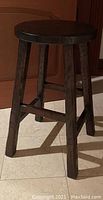 Single rustic mahogany wood bar stool showing round seat and angled legs with cross supports.