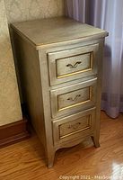 Side view showing the silver finish and gold trim on the three drawers.