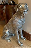Front view of seated dog statue on tile floor with furniture backdrop