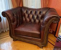 Front angle of brown leather tufted armchair showing rolled arms, button tufting, stud accents