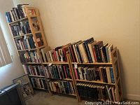 Photo of two short bookshelves and one tall bookshelf filled with books against a wall.