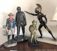 Full group of four warrior statues including cowboy, black soldier, bronze warrior with spear, and Asian warrior with shield