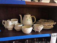 Teapot with cups, sugar bowl, creamer, and stacked saucers on shelf