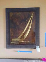 Front view of framed signed racing sloop artwork showing detail of sails and boat in a dark textured background.