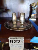 Salt and pepper shakers with tray displayed on wood surface.