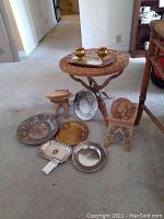 Overview photo of the wooden side table, four metal trays, and two wooden trays or plate holders arranged on the floor