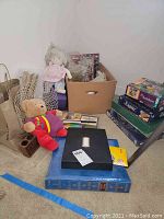 Wide shot showing assortment of craft supplies, toys, puzzles, and photo album arranged on the floor