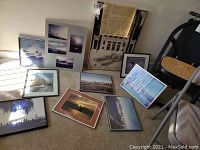 Nine framed art prints arranged on floor featuring Seattle history themes, cityscapes, and landscape photography. Various frame styles and sizes visible.