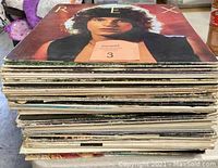 Stack of assorted vinyl records showing album spines and edges, visible wear on album jackets.