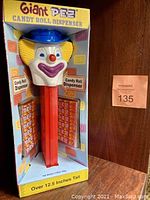 Front view of giant clown PEZ dispenser in original box with candy rolls displayed on sides