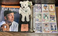 Photo showing black binder open to baseball cards, Beckett Tribute to Cal Ripken magazine, and Mark McGwire plush bear