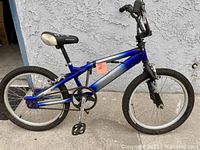 Side view of a blue and silver fade painted Mongoose bicycle with youth BMX style frame, black tires, and pedals visible.