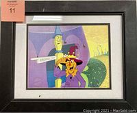Framed animation cel artwork showing a jester character pointing to an Emerald City sign, colorful whimsical background, measuring 17x14 inches