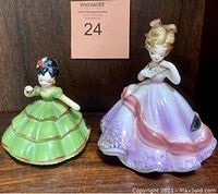 Front view of two figurines, one in green dress and one in lilac dress