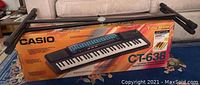 Full view of the boxed Casio CT-638 Tone Bank keyboard with stand displayed on top.