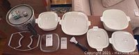 Photo of multiple Corning casserole dishes in white, various sizes, some with lids, one lid chipped