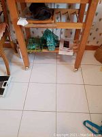 Photo showing the wooden cart with lower shelves holding glass cutting boards and flatware packaging, plus some cloth or napkins on top shelf.