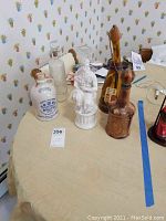Photo showing six vintage collectible decanters on a table including ceramic, glass, and porcelain pieces with various shapes and sizes