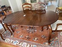 Top and side view of an Ethan Allen wooden dining table with curved legs and two removable leaves.
