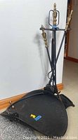 6 piece fireplace tool set in black metal with brass handle accents, includes stand, shovel, brush, poker, and tongs.