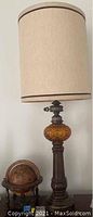 Photo showing tall table lamp with wooden turned base and beige fabric shade